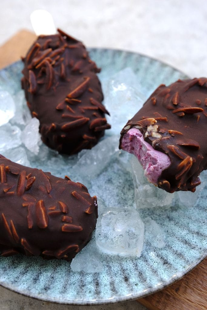 Cremiges Himbeer-Cashew-Eis am Stiel mit salzigem Karamell in knackiger Schokolade 